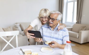 Happy old family couple talking with grandchildren using tablet , surprised excited senior woman looking at tablet waving and smiling.